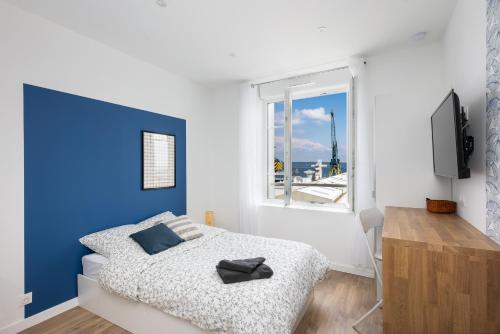 - une chambre blanche et bleue avec un lit et une fenêtre dans l'établissement En Distribil, à Brest