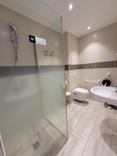 a bathroom with a shower and a toilet and a sink at Hotel Logis Au Moyne de Saire in Réville