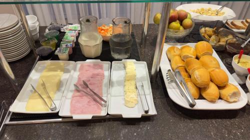 a table topped with plates of food with sandwiches and fruit at Campo Palace Hotel in Campo Mourão