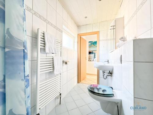 Un baño blanco con inodoro y lavabo. en Ferienhaus Méhaux 11, en Cuxhaven