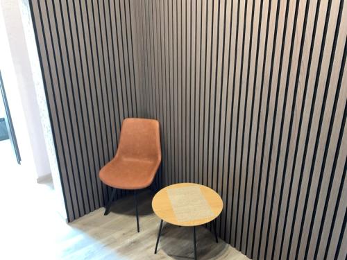 a chair and a table in front of a wall at Sweet Apartments in Šiauliai