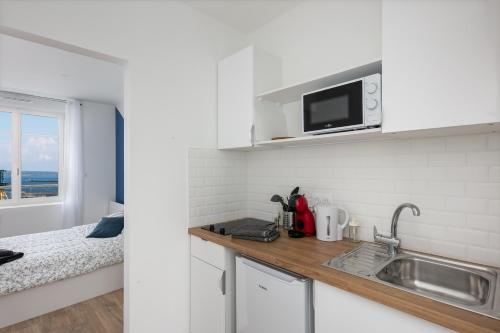 une cuisine blanche avec un évier et un micro-ondes dans l'établissement Big aille, à Brest