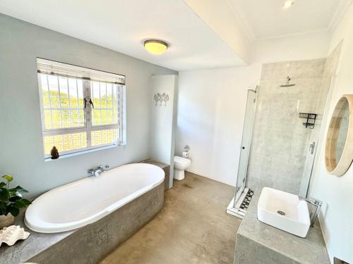 a bathroom with a tub and a toilet and a window at Tranquil Sunsets in Equestria