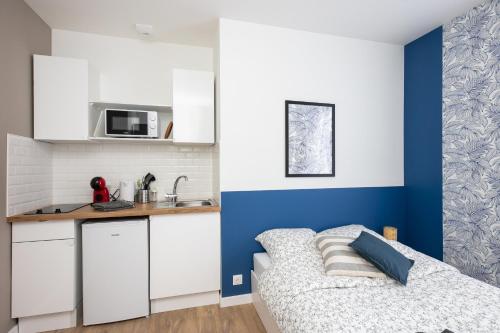 une cuisine avec des armoires blanches et un lit dans une chambre dans l'établissement Ma Doue, à Brest