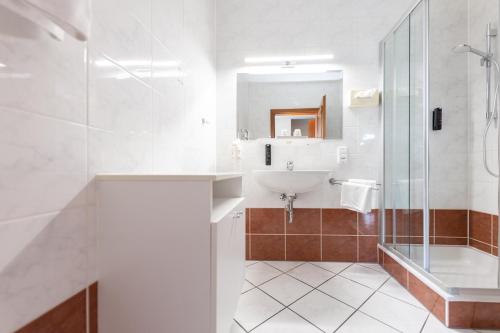a white bathroom with a sink and a shower at Parkvilla 11 in Fürstenfeld