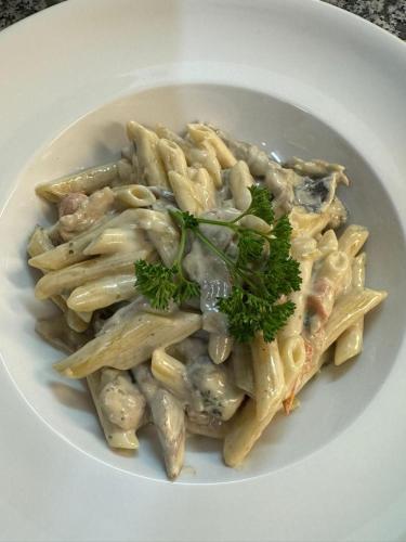 a white plate of pasta with meat and broccoli at Hotel im Kavalierhaus in Machern