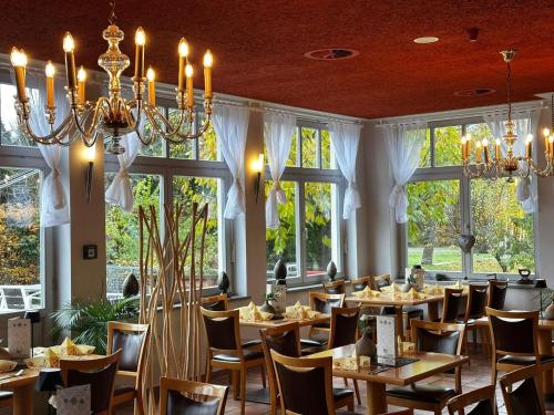 a dining room with tables and chandeliers and windows at Hotel im Kavalierhaus in Machern