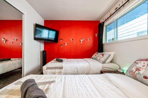two beds in a room with a red wall at Fresh & Comfy House with Hot Tub, Pool Table, & BBQ in Eugene