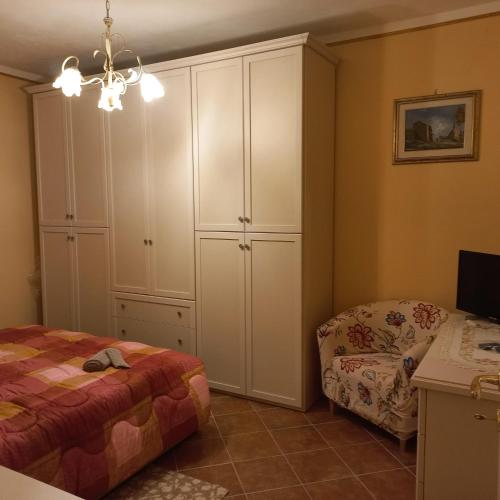 a bedroom with white cabinets and a bed and a chair at la Casa del Glicine in Mortaiolo