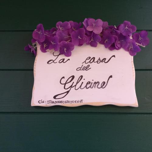 a sign with purple flowers on a wall at la Casa del Glicine in Mortaiolo