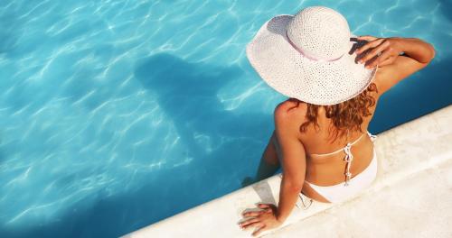 a woman in a hat sitting on the edge of a swimming pool at Harlow's Casino Resort & Spa in Greenville