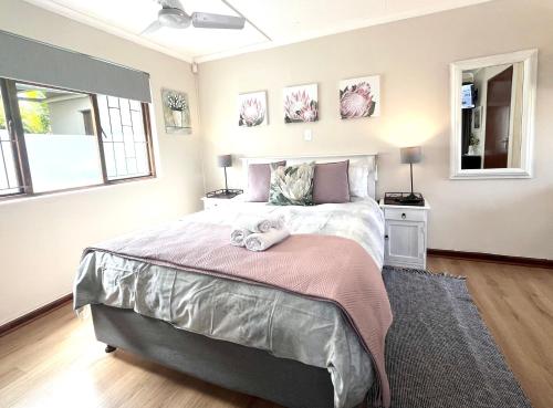 a bedroom with a large bed with two windows at Dolphin Circle Bed and Breakfast in Plettenberg Bay