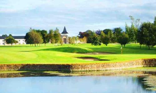 un campo de golf con un estanque en el primer plano en Lodge on Grounds of Ballykisteen Golf Resort, en Tipperary