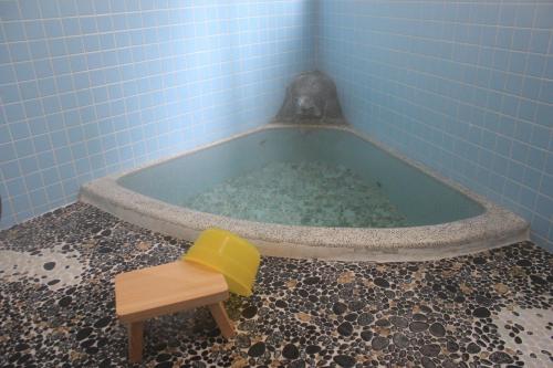 a blue tiled bathroom with a tub and a stool at Nozawa Dream in Nozawa Onsen