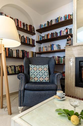a living room with a blue chair and bookshelves at Hotel Marina in Port de Soller