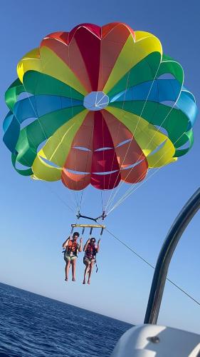 two people on a parachute over the water at Domina Coral Bay Sultan Vista Mare Uno in Banī Ghālib