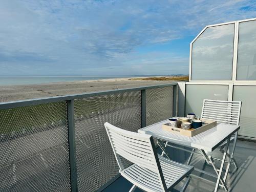 - un balcon avec une table et deux chaises et la plage dans l'établissement Face à la mer immense, à Cayeux-sur-Mer