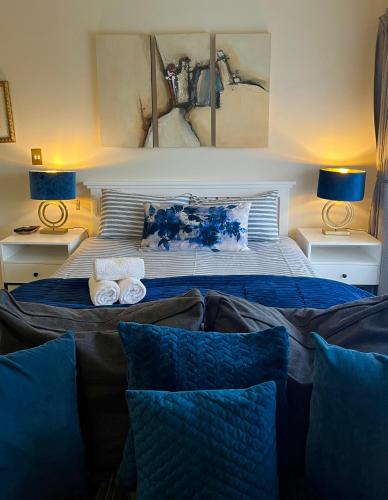 a bedroom with a bed with blue pillows and two lamps at Dolphin Circle Bed and Breakfast in Plettenberg Bay