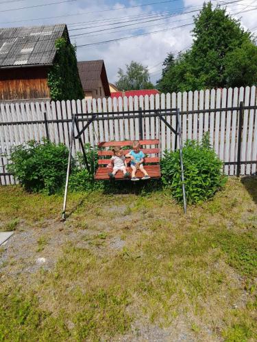 two children sitting on a bench in front of a fence at Klarissz Vendèghàz in Praid
