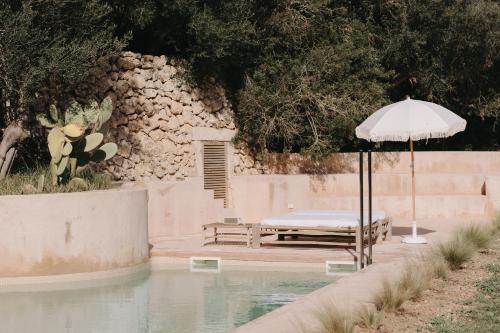 a pool with a table and an umbrella next to it at N a k e d S o l in Manacor