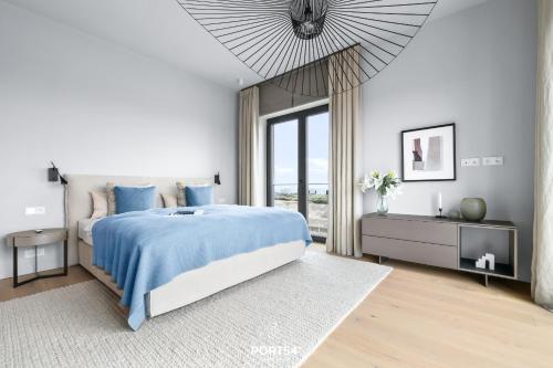 a white bedroom with a blue bed and a window at Penthouse Suite List auf Sylt in List