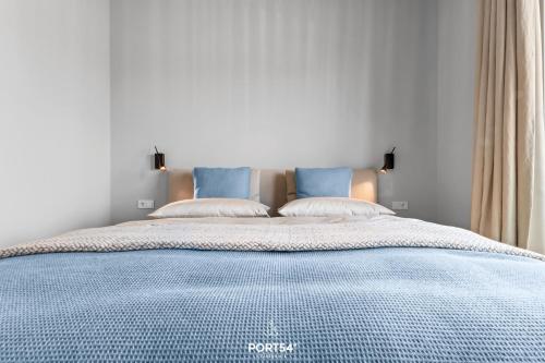 a bedroom with a blue bed with two pillows at Sunrise Suite List auf Sylt in List