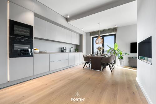 a kitchen with white cabinets and a dining room with a table at Ocean Breeze Suite List auf Sylt in List