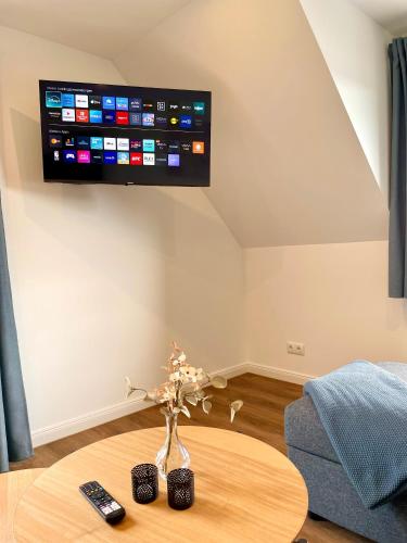 a living room with a table and a tv on the wall at Landhaus Evergreen in Wiesemscheid