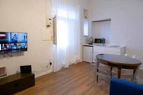 un soggiorno con un tavolo e una TV a parete di Il Gatto e Pirouette a Napoli