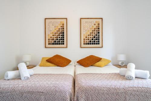 two beds in a room with two pictures on the wall at Apartamento Ses Botges - Formentera Break in Es Calo