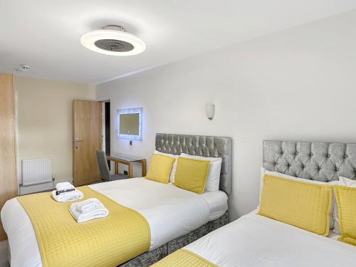 two beds in a room with yellow and white at Granada Apartments Berkeley in Blackpool