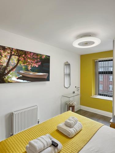 a bedroom with a yellow bed with towels on it at Granada Apartments Berkeley in Blackpool