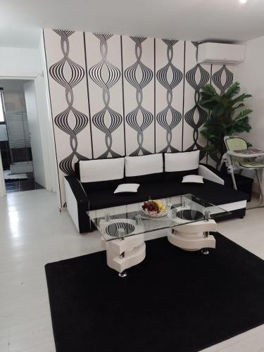 a living room with a black couch and a glass table at FLH - Apt Sofia in Şelimbăr