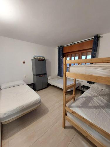 a room with two bunk beds and a refrigerator at Albergue La Costana in Oviedo