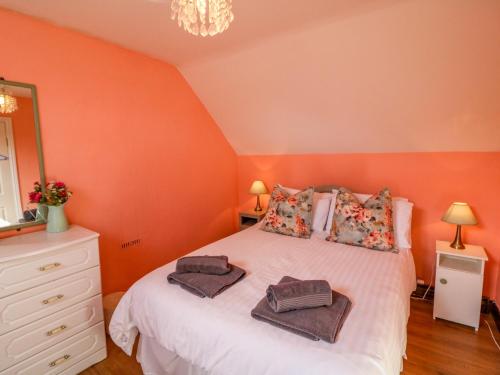 a bedroom with orange walls and a bed with towels on it at Sugarbush in Eyeries