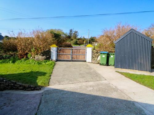 a driveway with a gate and two trash cans at Sugarbush in Eyeries