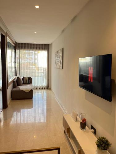 ein Wohnzimmer mit einem Sofa und einem TV an der Wand in der Unterkunft Signature Leving 119 in Casablanca