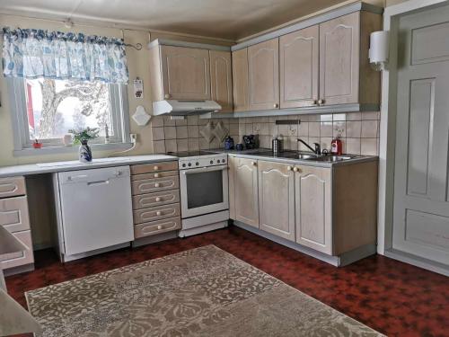 une cuisine avec des armoires blanches et un évier dans l'établissement Feriehus ved Fjellfroskvatnet, à Skjold