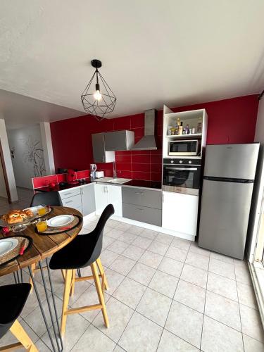 a kitchen with white appliances and a table with chairs at La Perle de Rivière Sens - Vue Mer, proche Plages in Gourbeyre