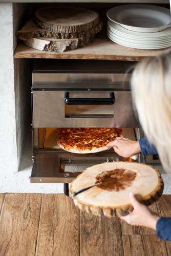 a person taking a pizza out of an oven at Chalupa Libverda in Lázně Libverda