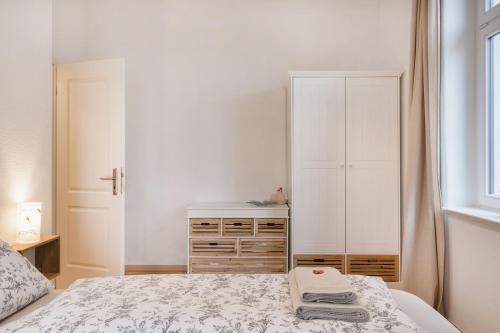 a white bedroom with a bed and a dresser at Holiday Home With EV-Station & Netflix in Dresden