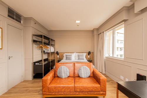 a bedroom with a bed with an orange couch at STD - Anora Spaces - Stadium Alphaville in Barueri