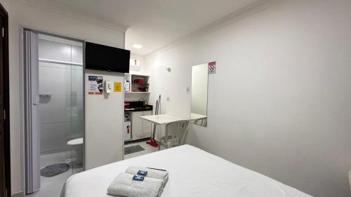 a small white room with a bed and a refrigerator at John- R Apart-hotel Curitiba Jardim Botânico in Curitiba