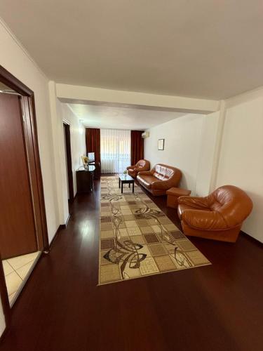 a living room with leather chairs and a rug at Hotel Ciric in Iaşi
