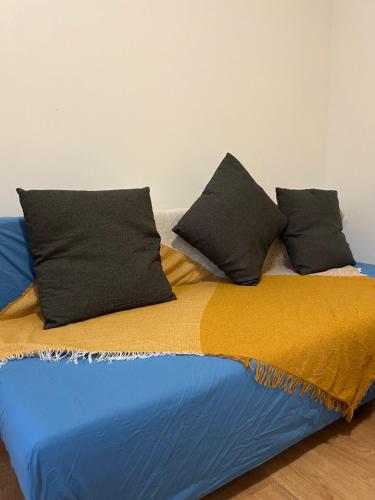 a bed with black pillows on top of it at Gagny charmant deux pièces très calme in Gagny
