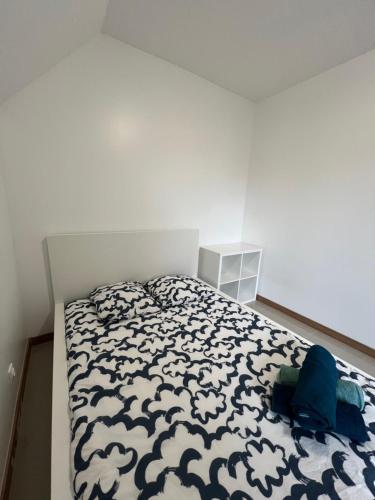 a bedroom with a bed with a black and white comforter at Gagny charmant deux pièces très calme in Gagny