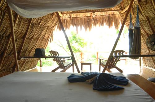 a bed in a tent with two chairs in a room at Posada del Cerro in El Remate