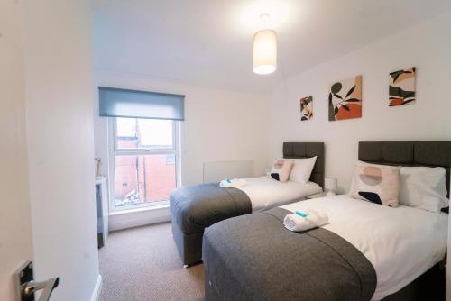 a bedroom with two beds and a window at Stunning New Town Centre flat in Wigan in Wigan