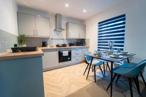 a kitchen with a table and blue chairs at Stunning New Town Centre flat in Wigan in Wigan