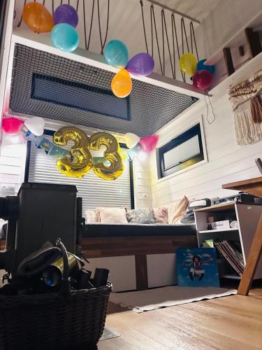 a room with a bed with balloons and a desk at Heaven Reset Spa Luksusowy Glamping Jacuzzi w Naturze Blisko Warszawy in Korczew